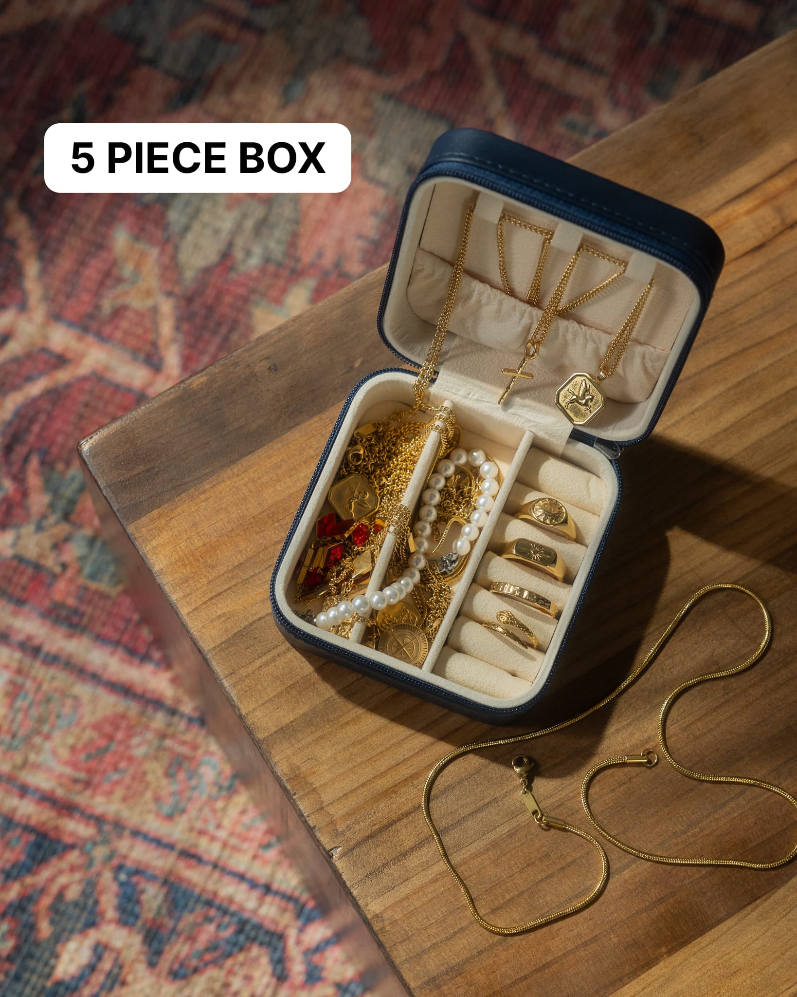 Open jewelry travel case on a wooden table, showing gold chains and pendants as part of the 5 piece box offer.