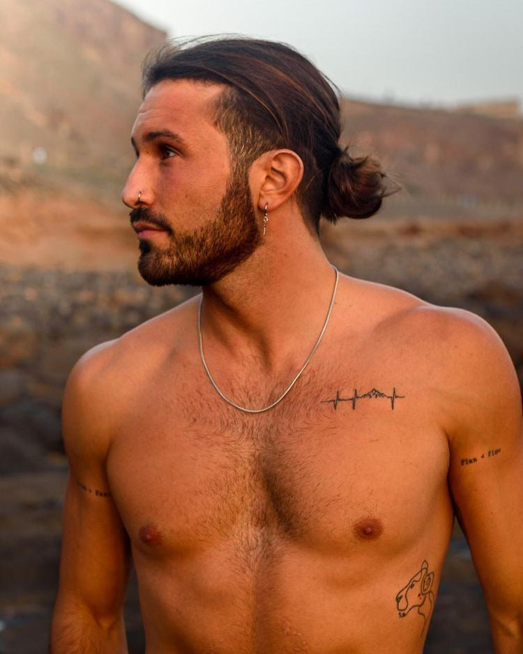 Profile view of a man wearing layered Sunset Silver Chain necklaces outdoors.