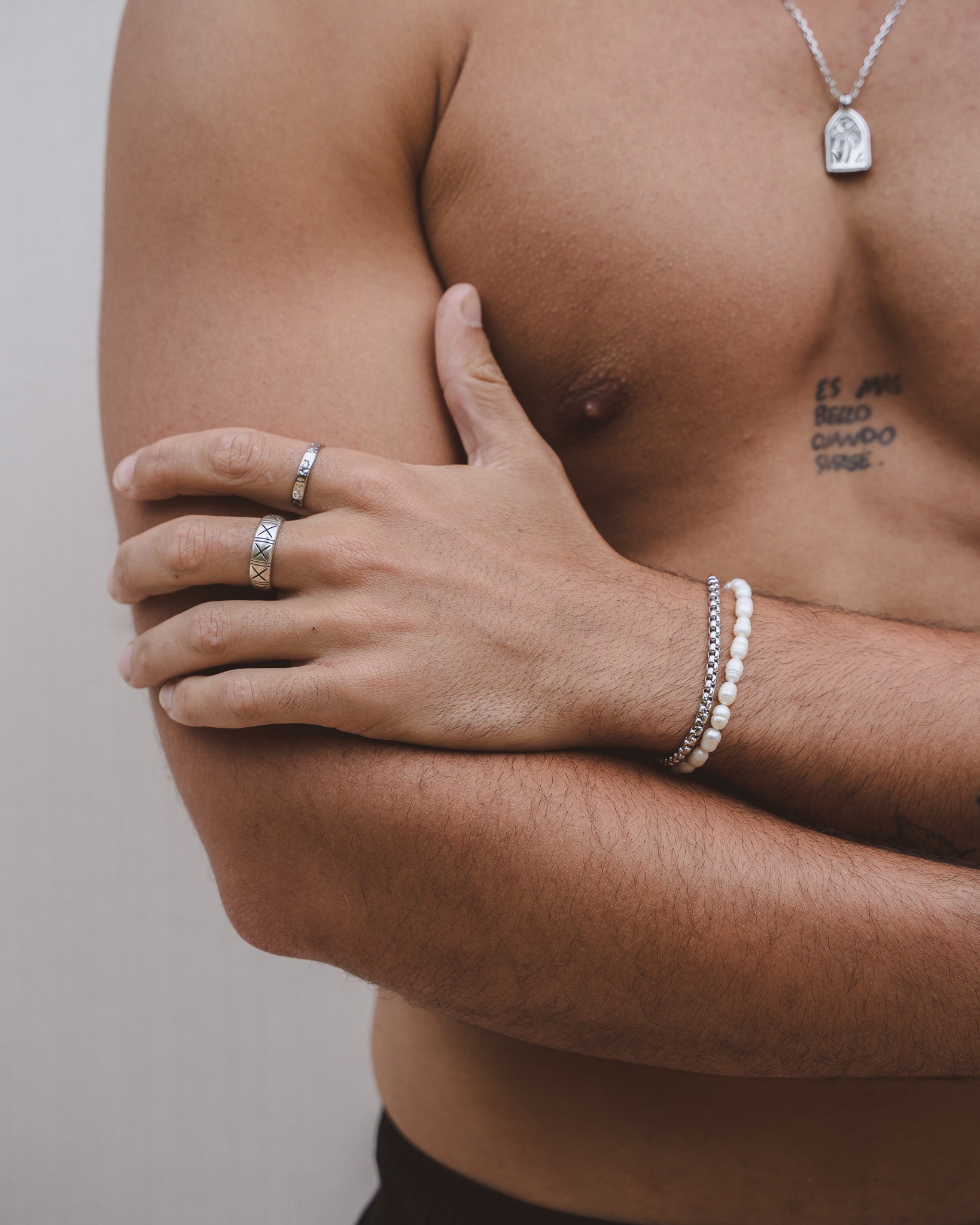Close up of a hand wearing a geometric patterned silver ring on a finger.