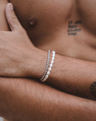 Belize Pearl Bracelet with Caribbean freshwater pearls on a wrist beside a silver chain bracelet