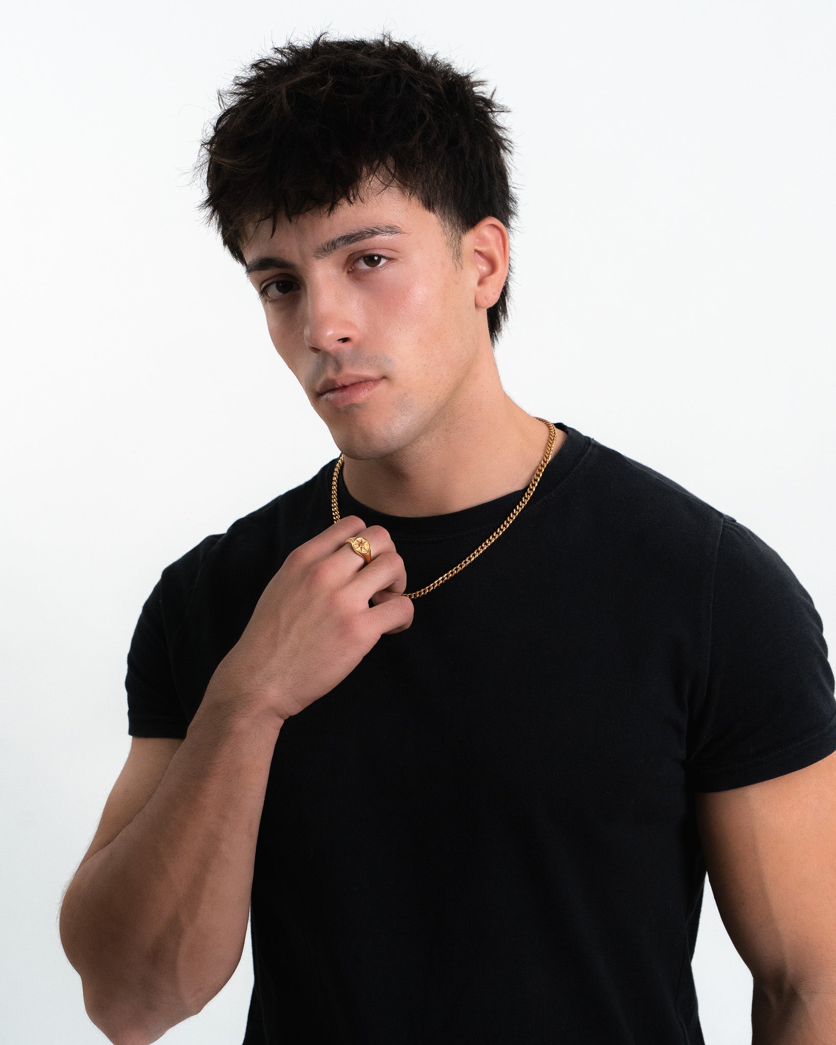 Man wearing a gold star ring and layered gold chains on a black shirt