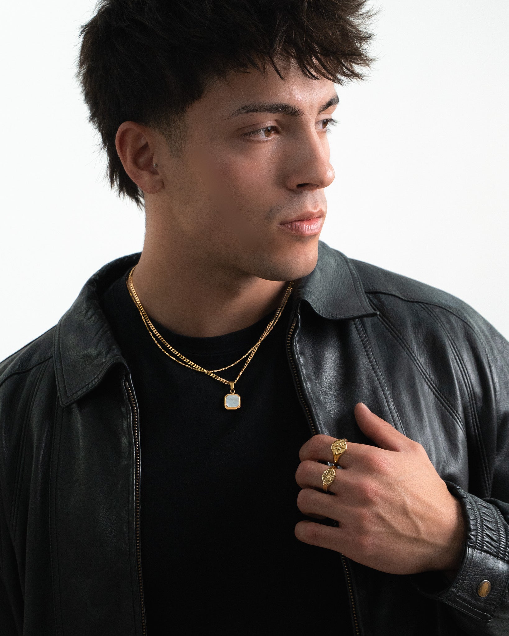 Close up of a gold star ring on a finger with a leather jacket and necklace in view