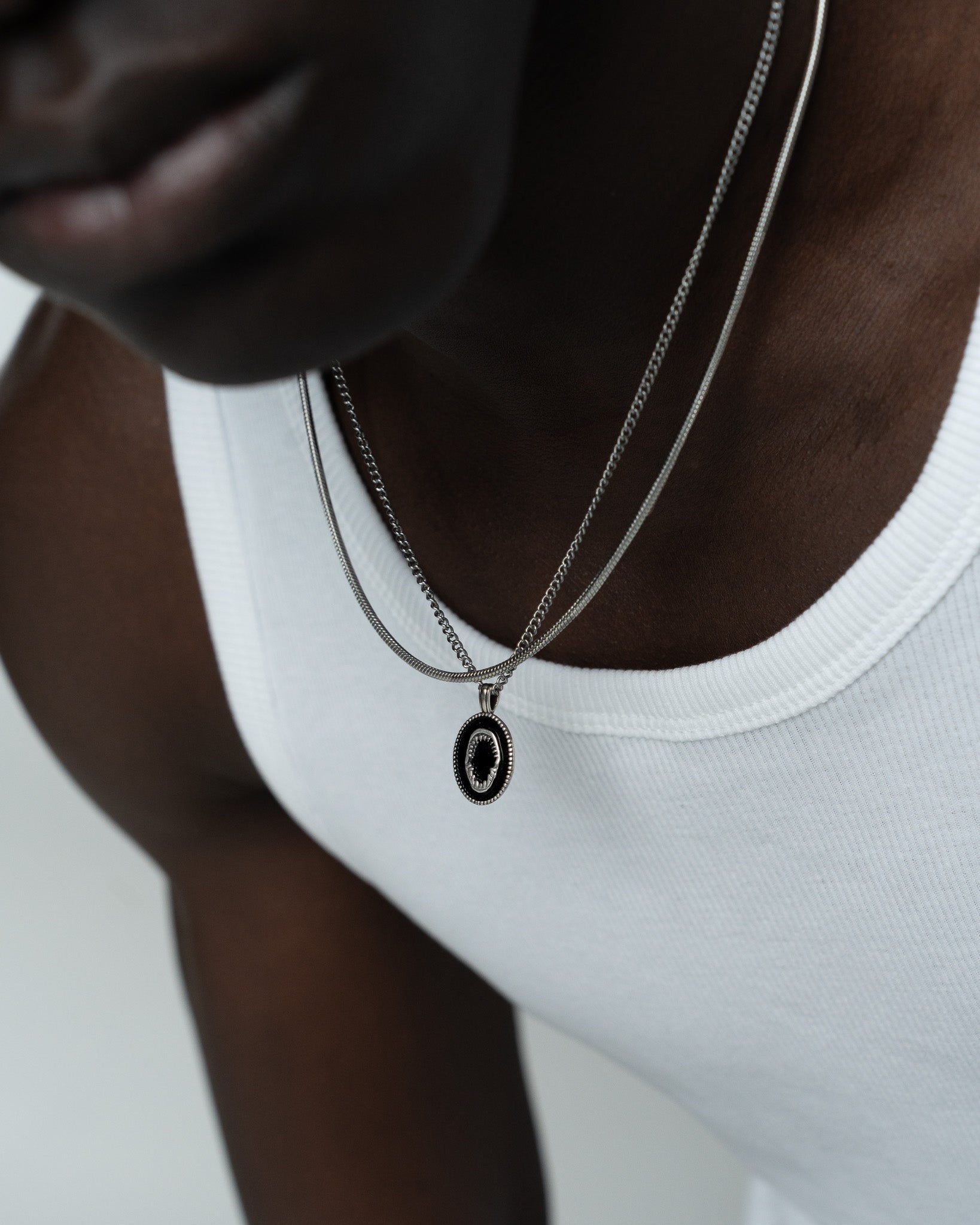 Close up of layered silver chain necklaces with a pendant resting on the chest