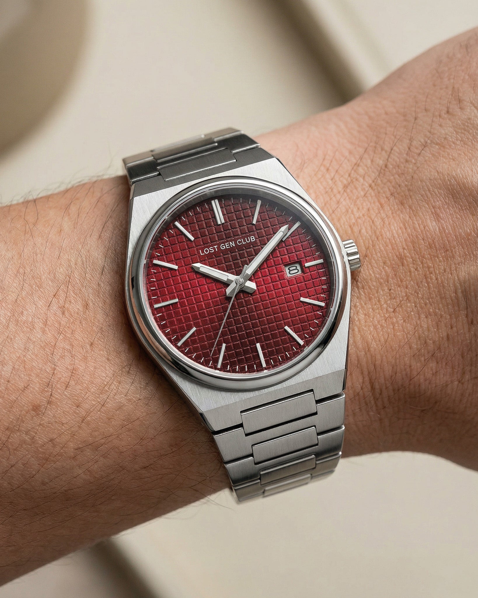 AUREN watch on a wrist with a red textured dial and stainless steel bracelet.