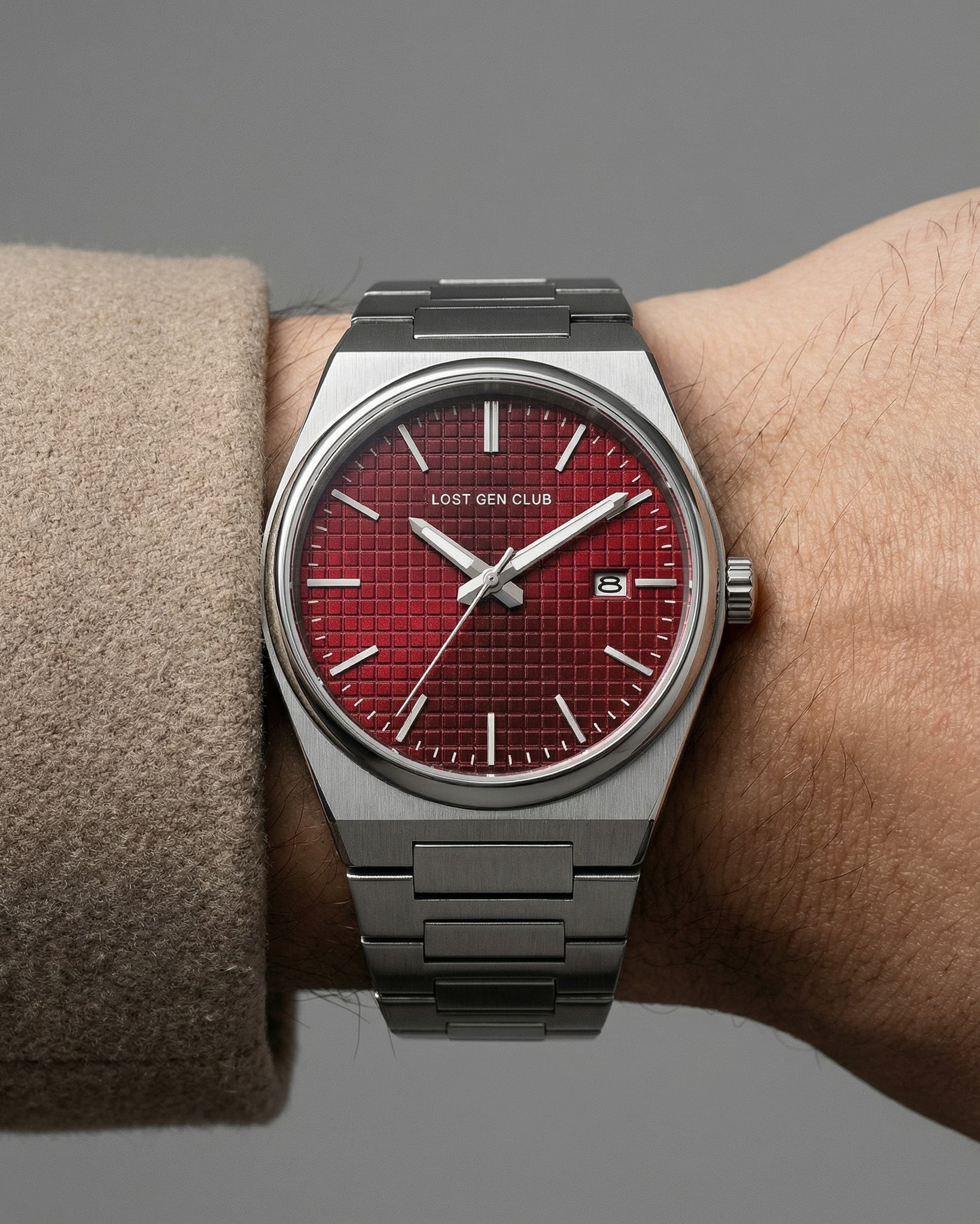 AUREN watch on a wrist wearing a tan coat, red dial with silver case and bracelet.