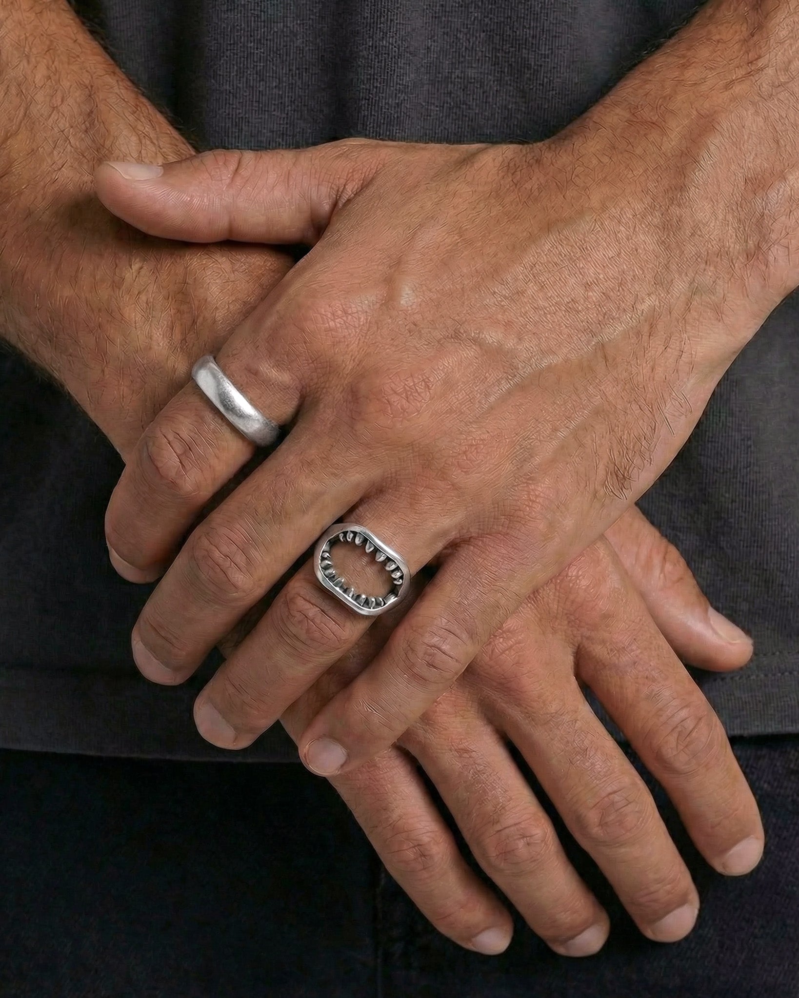 Silver band ring with toothed inner edge worn on finger
