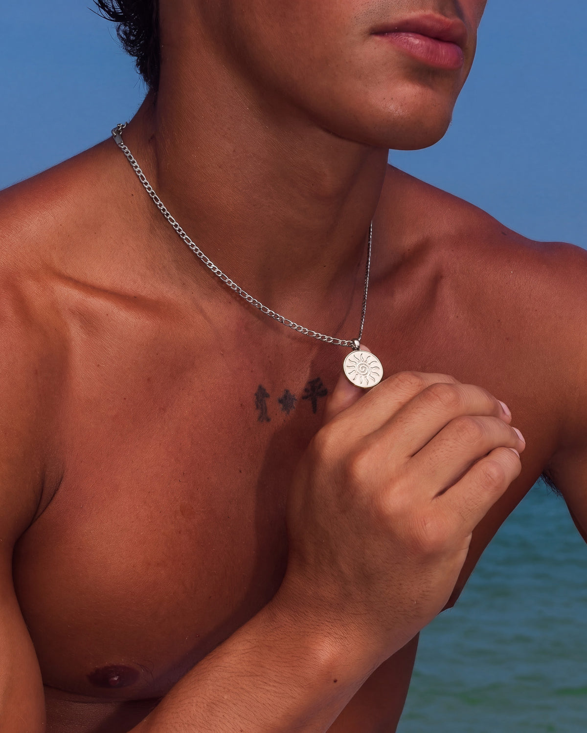Porträt einer Person mit der silbernen Energy Kette mit Sonnenanhänger am Schlüsselbein.