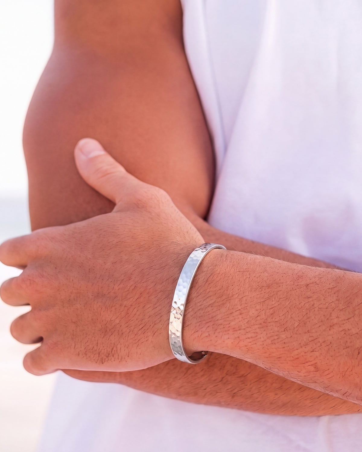 Pulsera de plata martillada en la muñeca de un hombre con camisa blanca