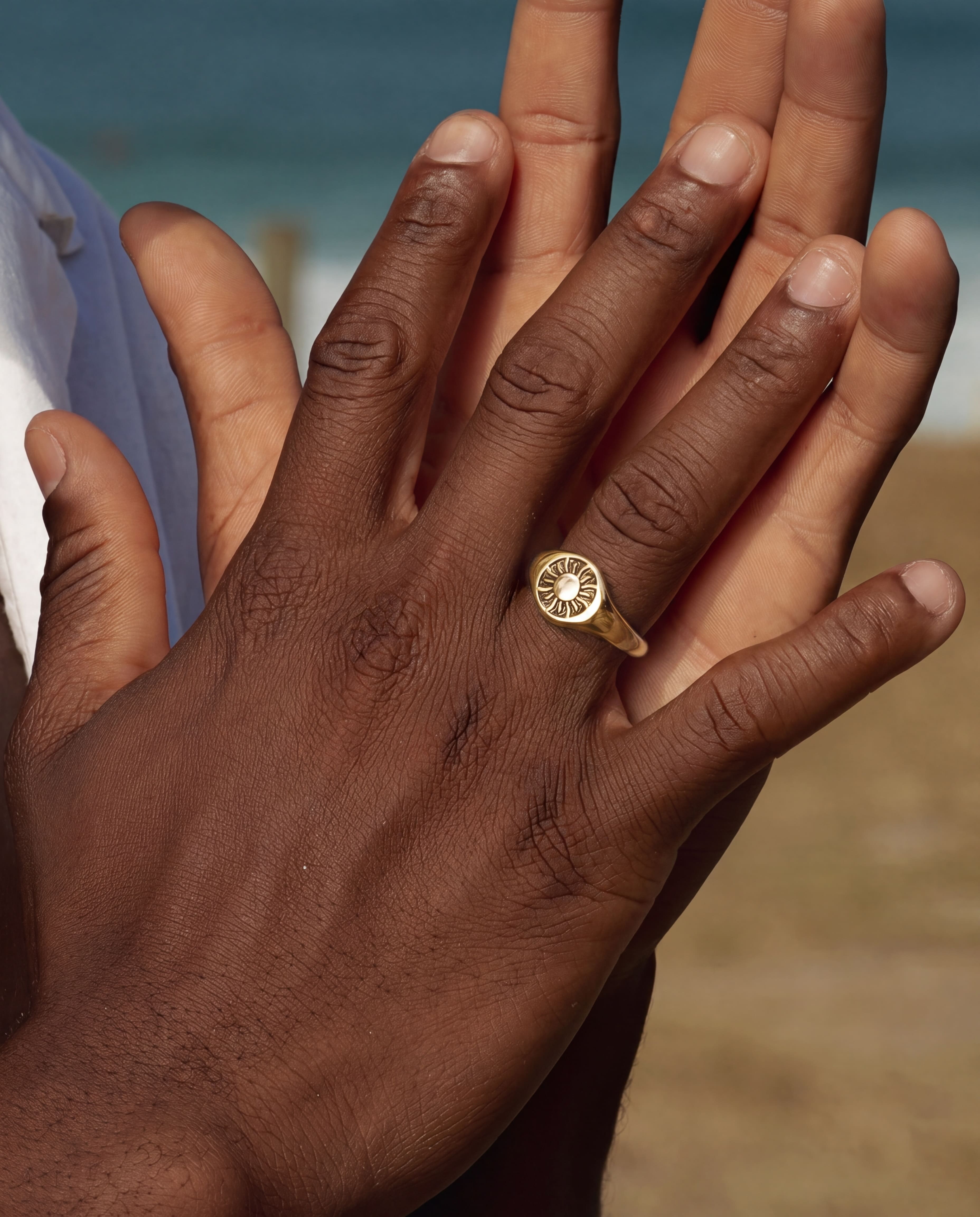 Close up of hands wearing a Helio Gold Ring with a sunburst motif
