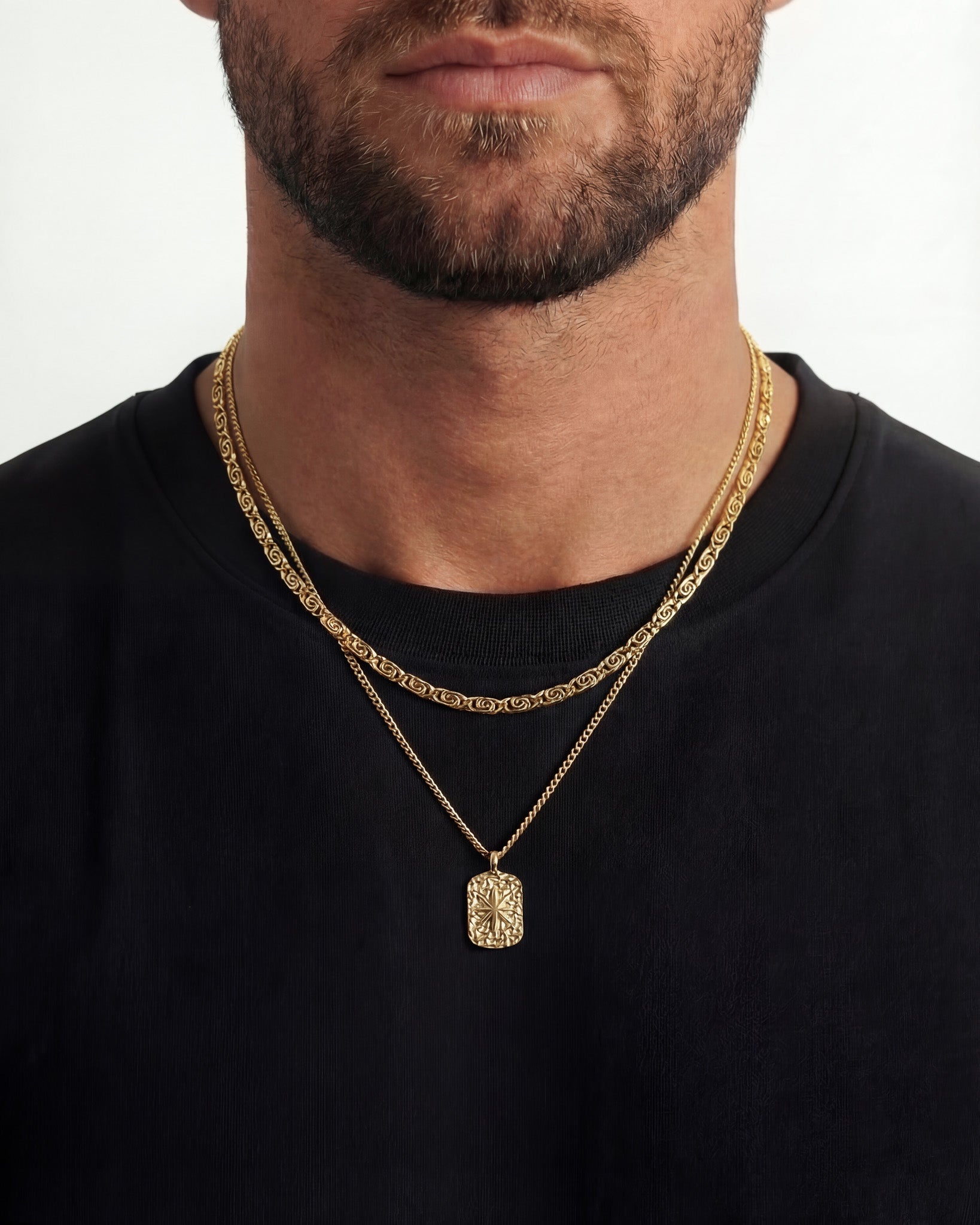 Layered gold chain necklace with a decorative square pendant featuring a star motif.