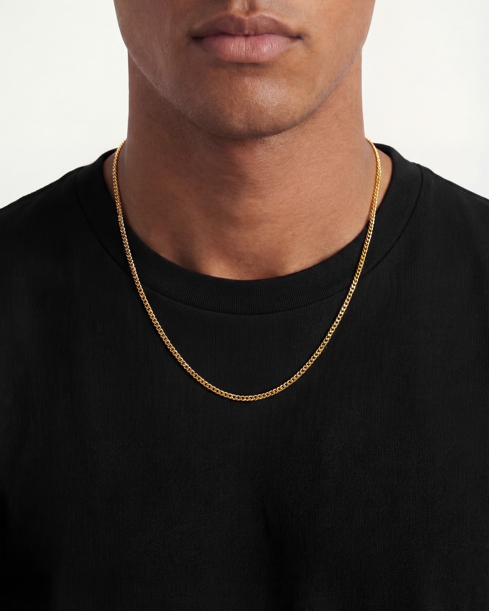 Gold KUBU Cuban link chain worn around the neck on a person wearing a black shirt