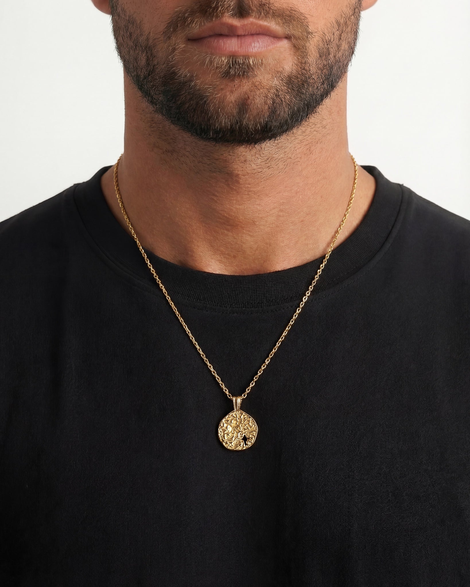Man wearing MIST GOLD NECKLACE with a textured round pendant resting on his chest