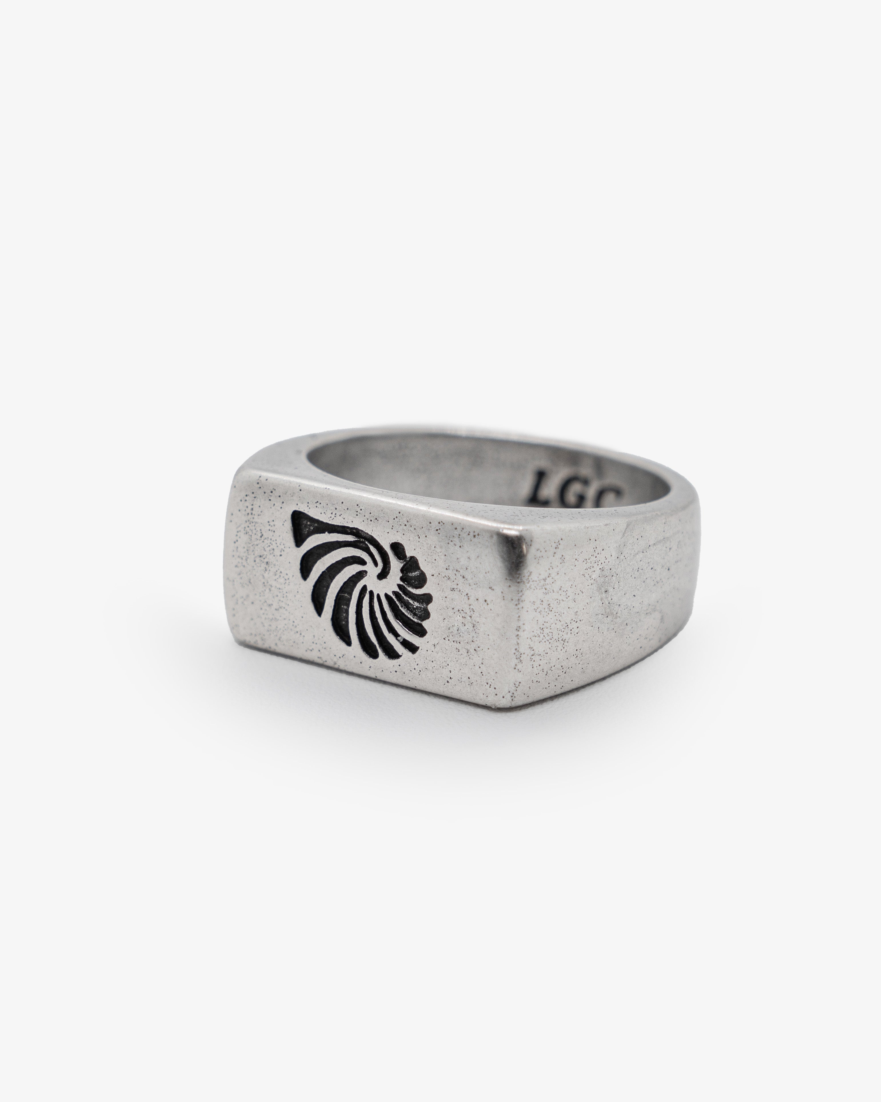 Close-up of a speckled grey shell ring with a black shell design on its side.