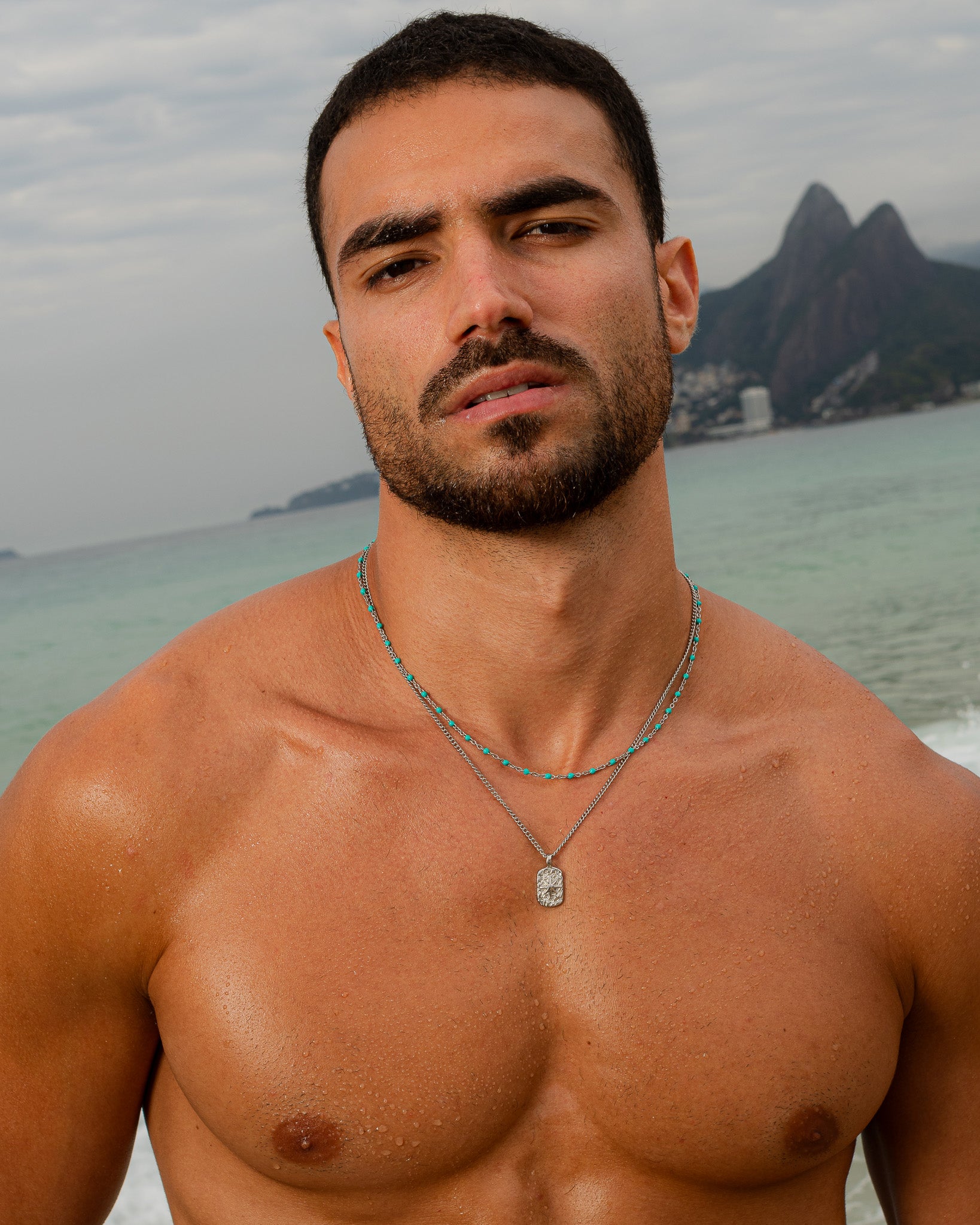 Man wearing a silver necklace with turquoise beads at the beach