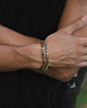 Two moss agate and hematite bead bracelets with gold spacers worn on a forearm