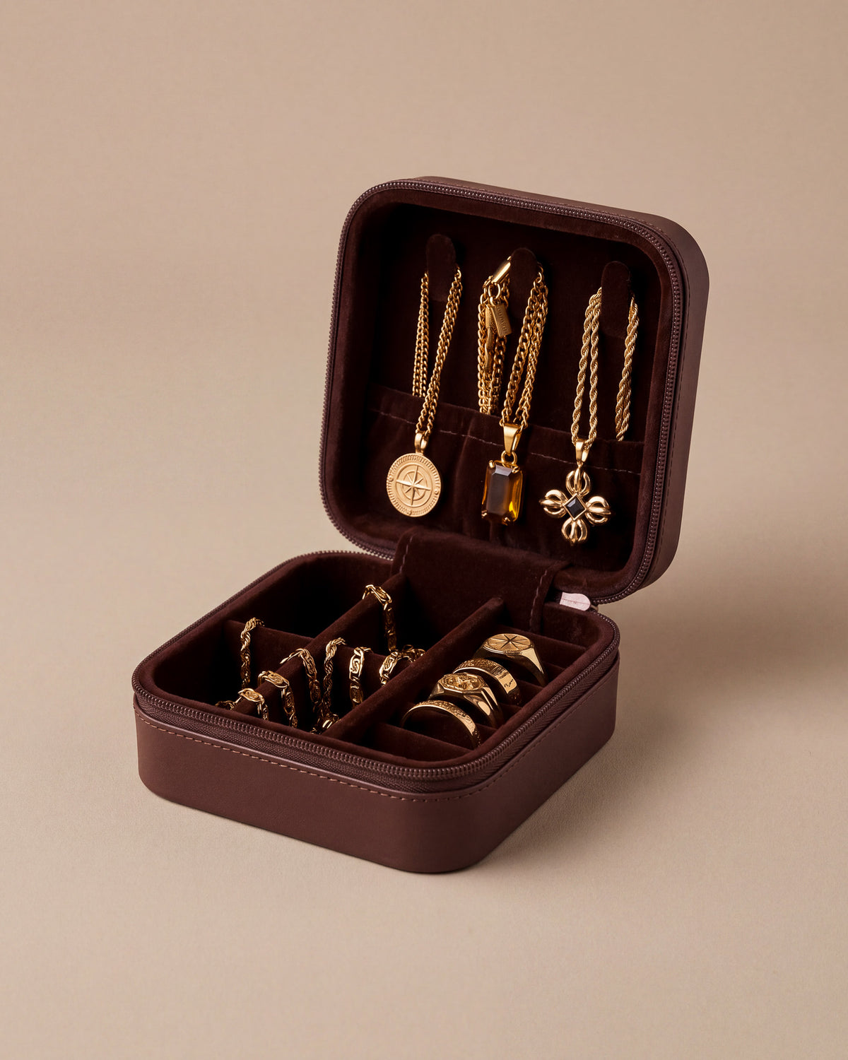 Geöffnete bordeauxrote Schmuck-Reisebox mit Goldketten und Anhängern