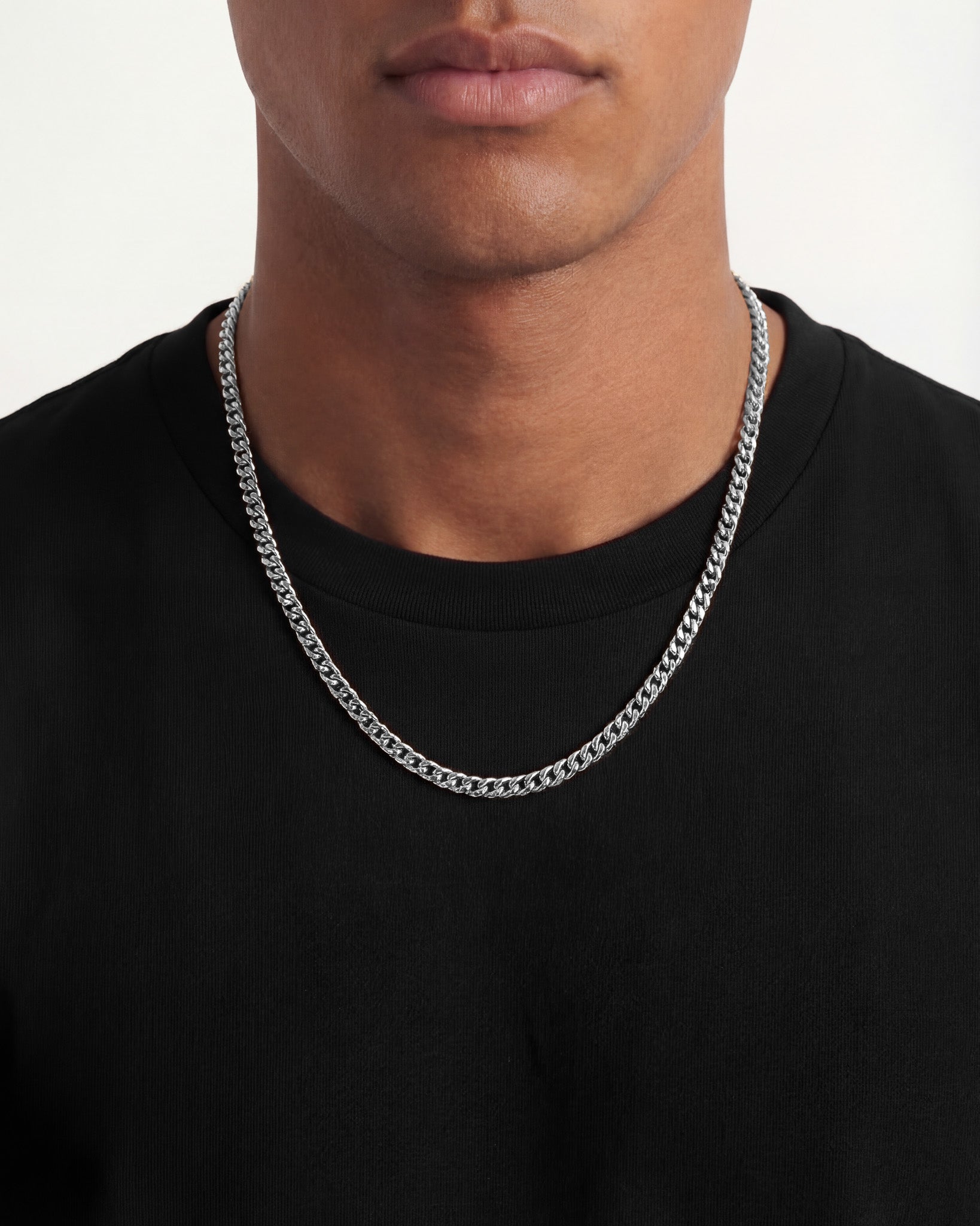 Close up of a silver chain necklace resting on a black t shirt
