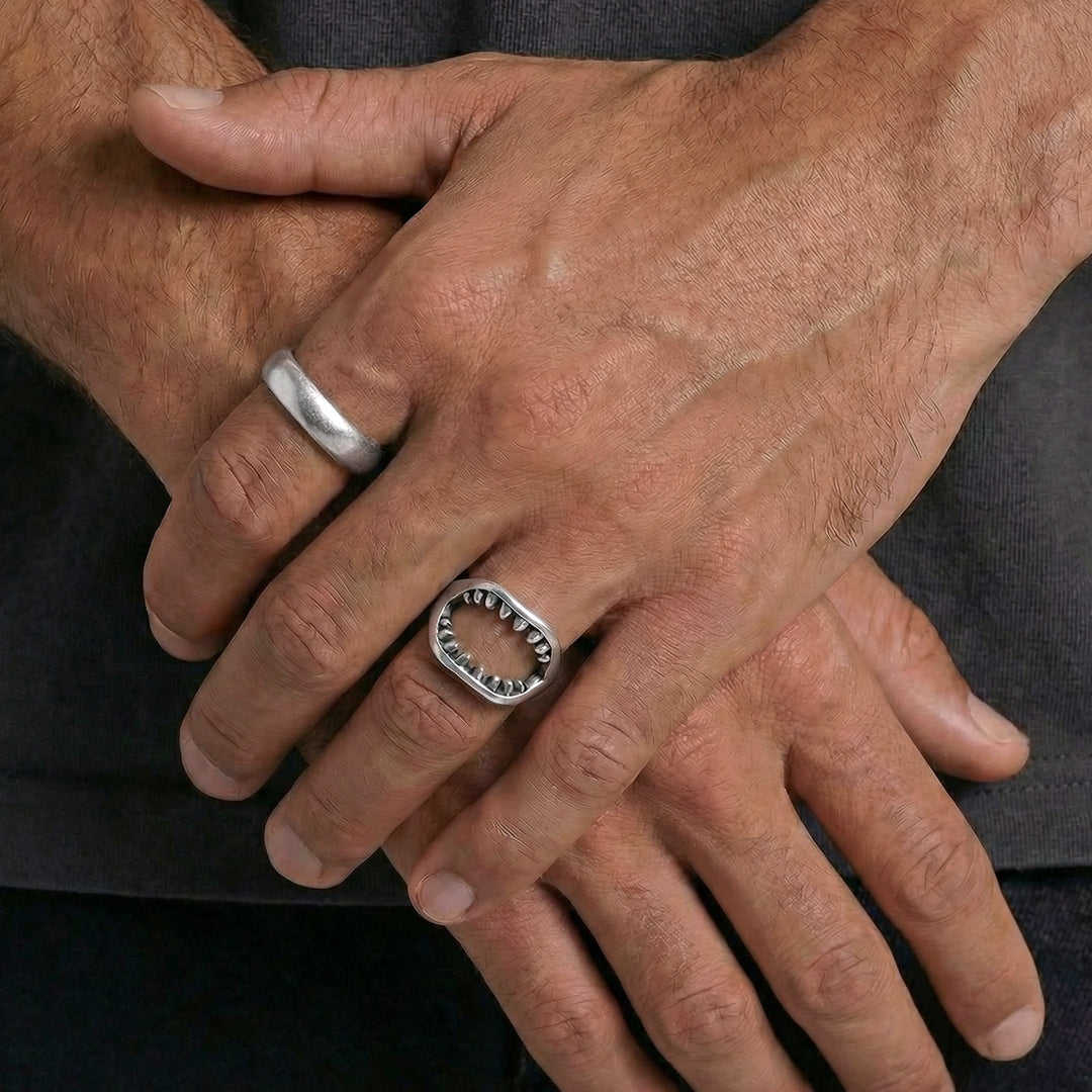 Hands with rings a chunky silver band on the index finger and a circular ring with a jagged inner edge on the middle finger