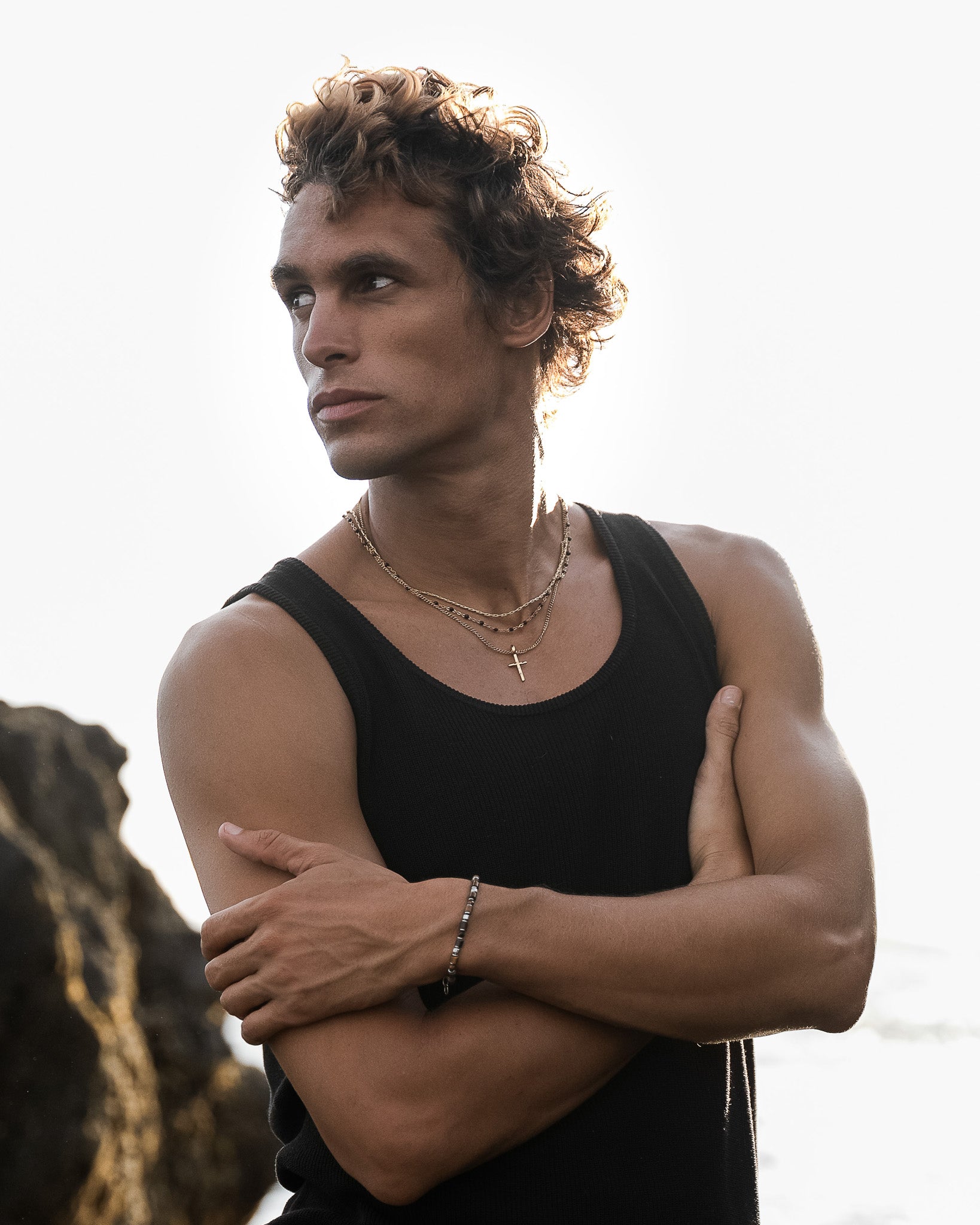 Man wearing white shorts shows a blue beaded bracelet with silver links on his wrist