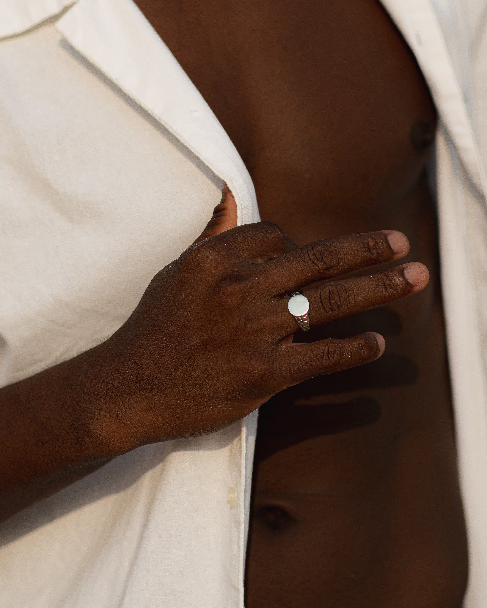 Silver Eden Ring with a round white face on the ring finger of a dark-skinned hand.