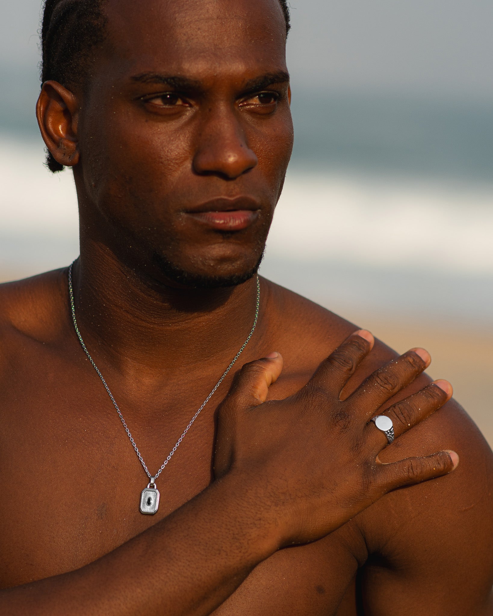 Close up of a man wearing a silver EDEN ring with a round face on his ring finger, necklace visible.
