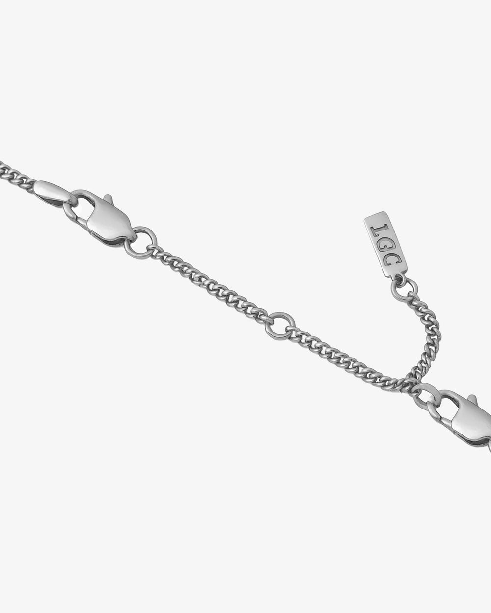 Close up of a silver 8 cm chain extender with a lobster clasp on a pale background