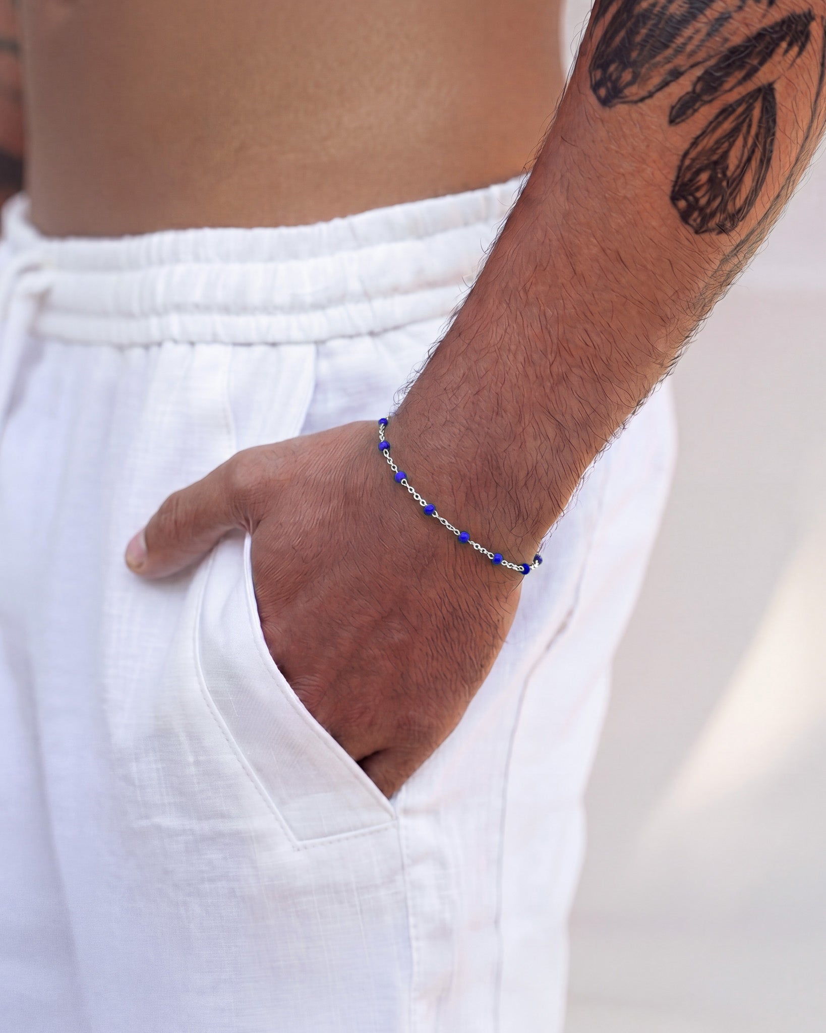 Silver bracelet with blue beads wrapped around a man's wrist