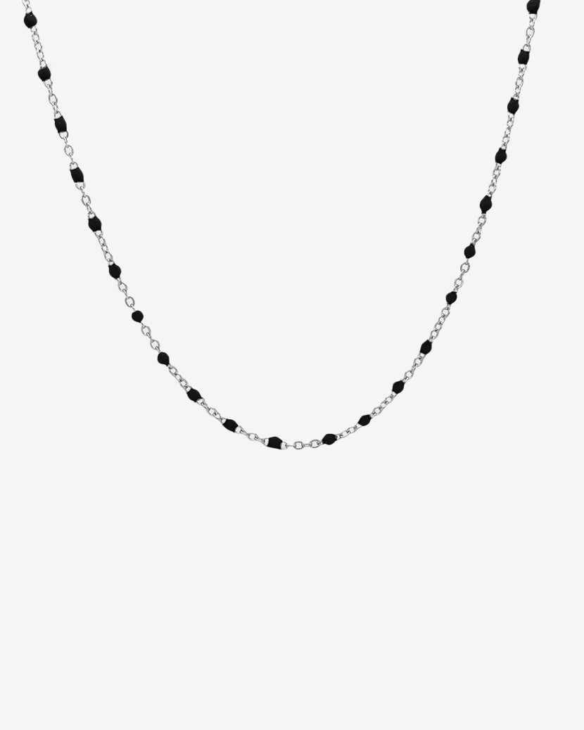 Silver chain necklace with evenly spaced black beads displayed against a white background