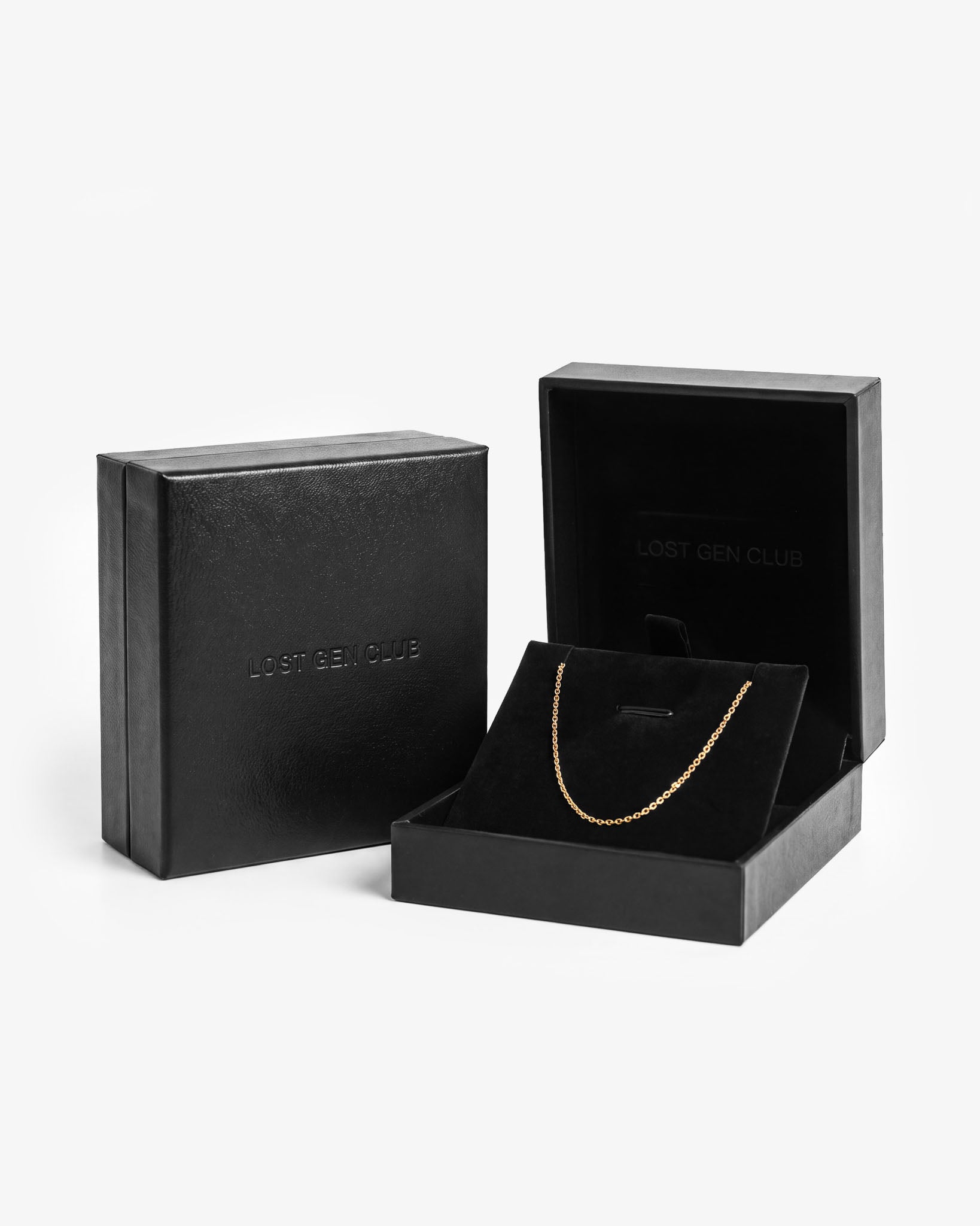 Schwarze Premium-Geschenkbox geschlossen und geöffnet, mit geprägtem LOST GEN CLUB Schriftzug auf dem Deckel und einer Goldkette auf dem Samteinsatz