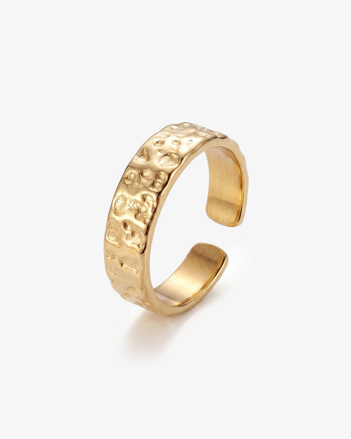 Anillo dorado martillado de 6 mm con superficie texturizada en el dedo de un hombre.