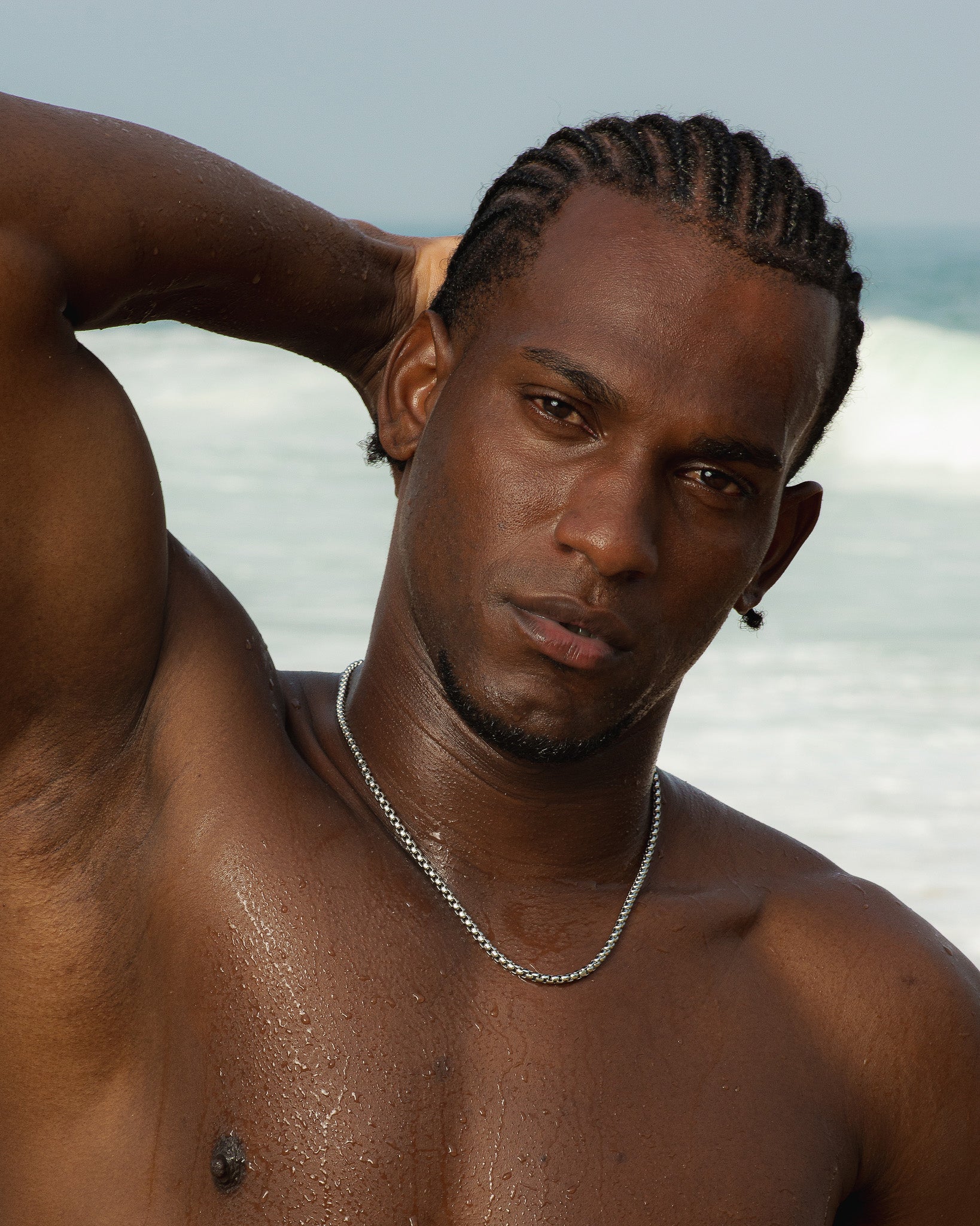 Man at the beach with Noir Silver Chain around his neck and a hand resting on his head.