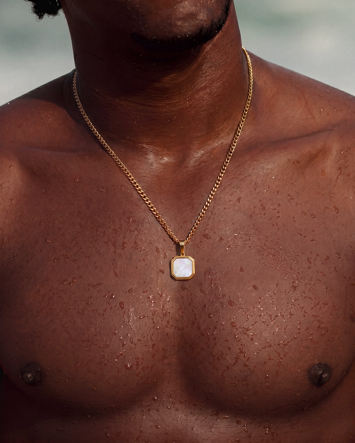 NOVA GOLD NECKLACE close-up of an octagonal pendant with a white stone center on a gold chain