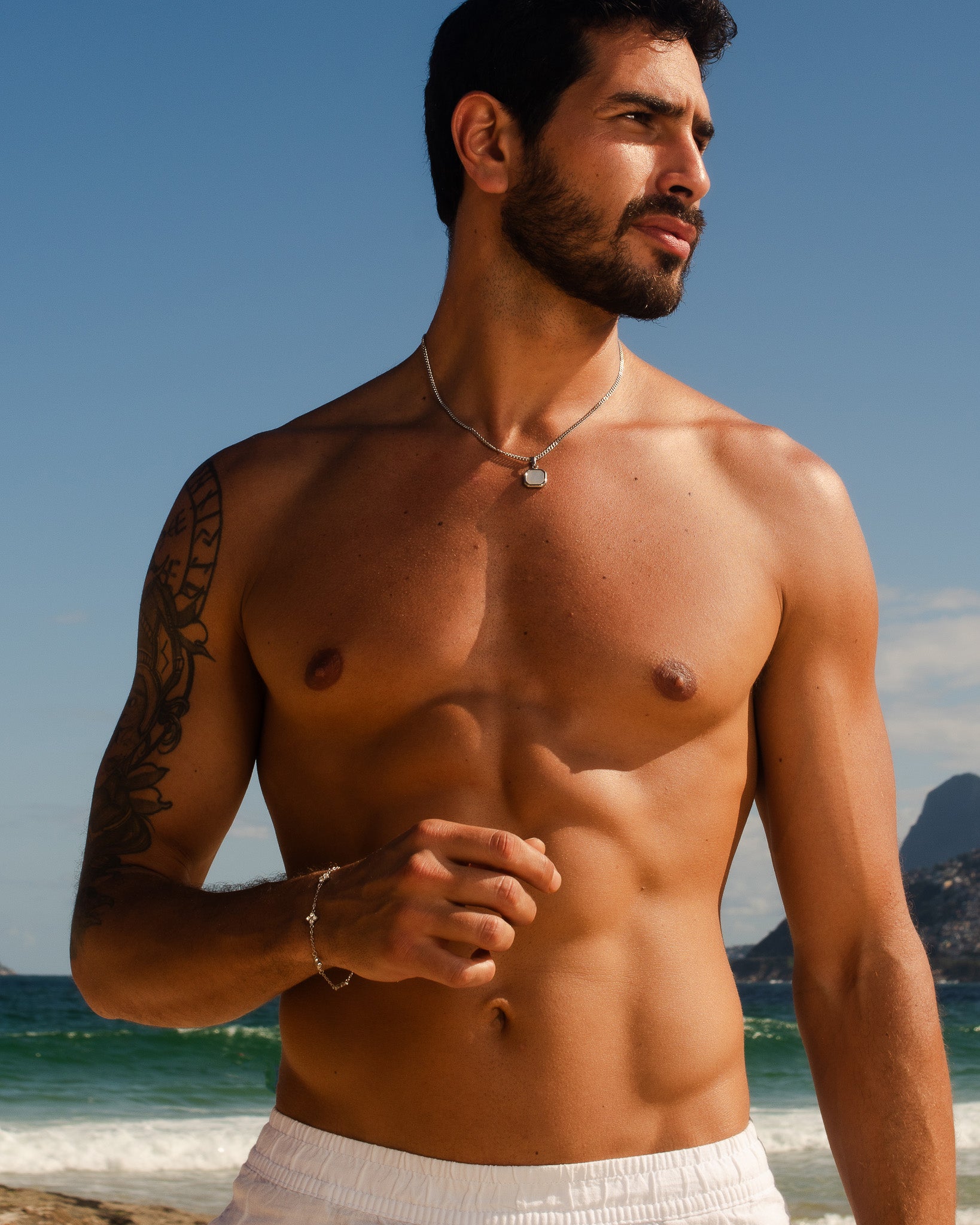 Man wearing Nova Silver Necklace with square milky pendant at the beach