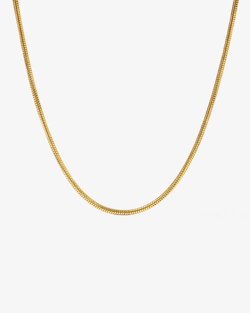 Sunset gold chain with 2 mm wide links laid across a light stone background