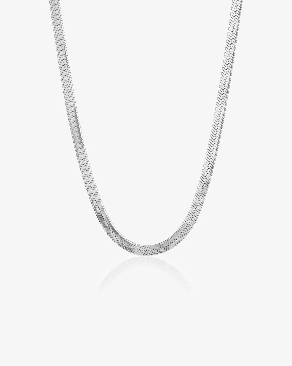 Close up of a silver wavy chain necklace against a white background with a subtle reflection